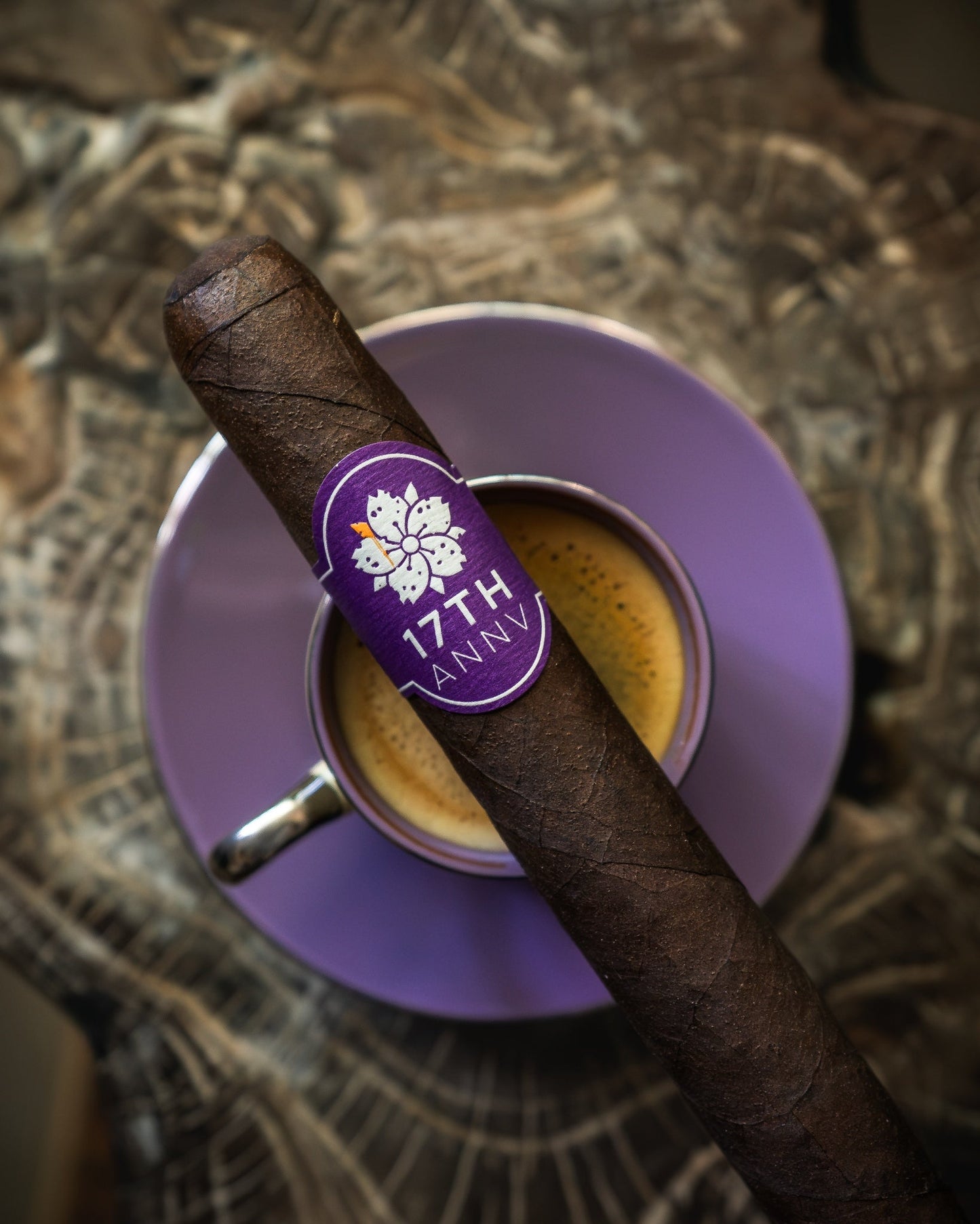 Room 101 17th Anniversary toro cigar with purple anniversary band resting on an espresso cup